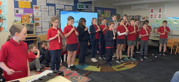 Class of students standing playing recorders